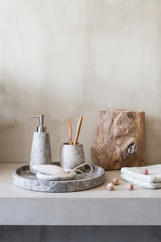 Minimalistisches Badezimmerdekor mit Steinaccessoires und Holzelementen auf einer Theke.