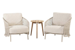 Zwei Sessel Puccini Latte von 4Seasons Living im modernen Design mit Seil-Geflecht und beiger Polsterung flankieren einen kleinen runden Holztisch.