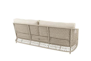 Die Rückansicht des 4Seasons 3-Sitzer-Sofas Puccini Latte zeigt ein beiges Korbgeflechtdesign mit weißen Kissen und einem einzigartigen Seilgeflecht, das den modernen Look verstärkt und sich ideal für jede Sofalandschaft im Freien eignet.