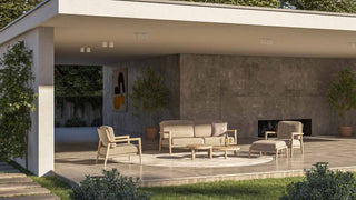 Eine moderne Außenterrasse präsentiert das 4Seasons Lounge-Set Julia 4-tlg., ein wetterfestes beiges Set, ergänzt durch Betonwände und Topfpflanzen, wodurch ein einladender schattiger Bereich entsteht.