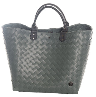 Der Witzgall Shopper Klassik 5110, eine grüne gewebte Tragetasche der Marke Witzgall, verfügt über elegante schwarze Kunstledergriffe und ein kleines rundes Emblem in der unteren rechten Ecke.