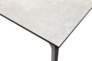 Nahaufnahme des KETTLER Gartentischs, ein moderner Tisch von Kettler mit hellgrauer Oberfläche und schwarzen Beinen, der minimalistisches Design zeigt.