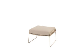 Der 4Seasons Fußhocker Albano Latte verfügt über ein beiges Kissen, schlanke Metallbeine und ein stilvolles Seil-Design, das sich vor einem strahlend weißen Hintergrund abhebt.