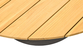 Nahaufnahme des runden Tierra Outdoor-Ess-Tischs Morena Ø150cm mit einer Tischplatte aus hellem Teakholz und Plankendesign, gepaart mit anthrazitfarbenen, pulverbeschichteten Aluminiumbeinen für Eleganz.